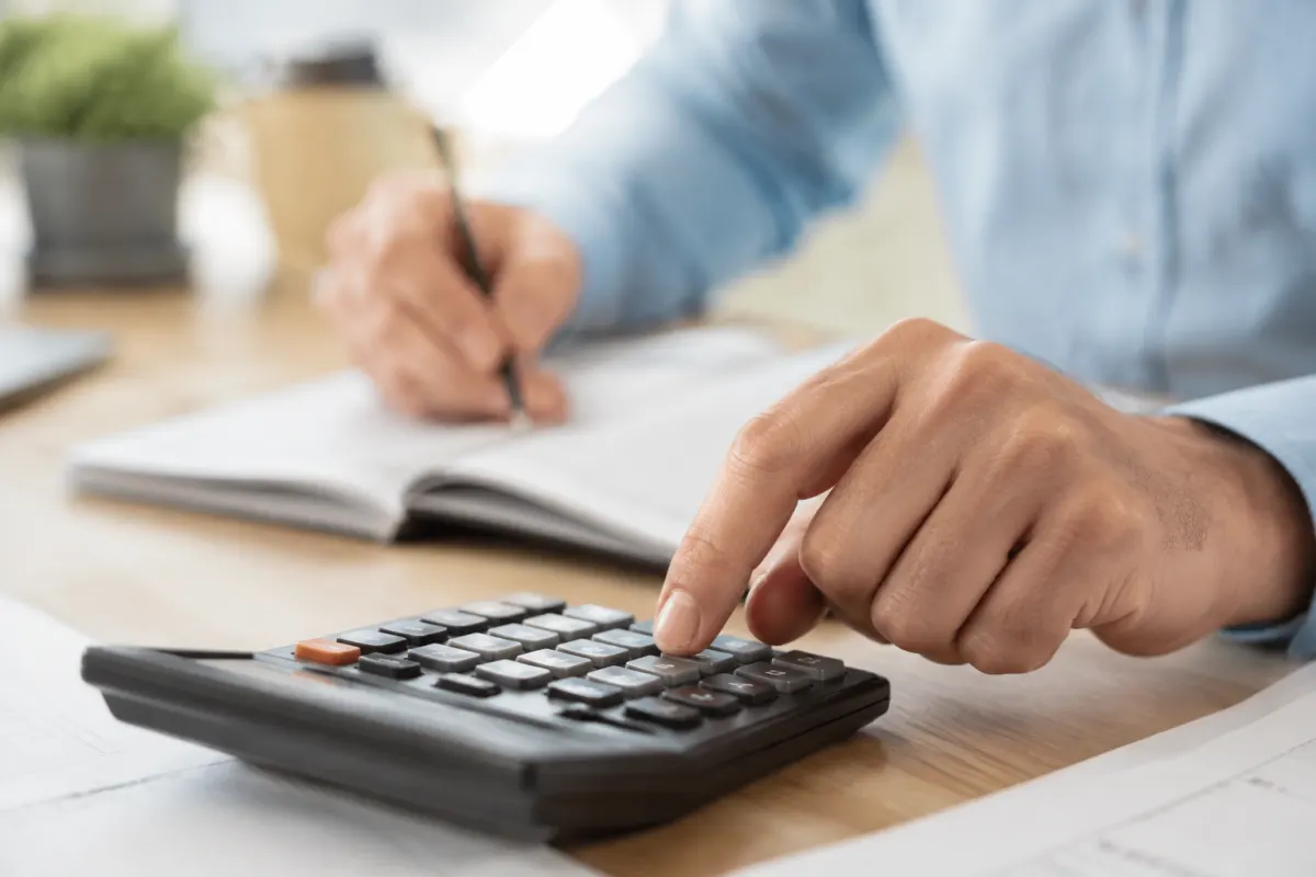 Une main tenant un crayon sur un bilan financier avec des calculs de déduction fiscale
